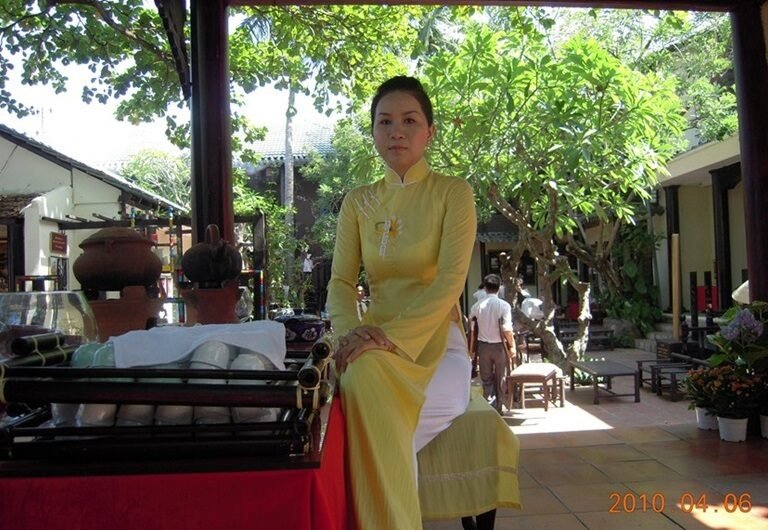 A Vietnamese woman in her yellow ao dai serving as a hostess in a club in Nha Trang