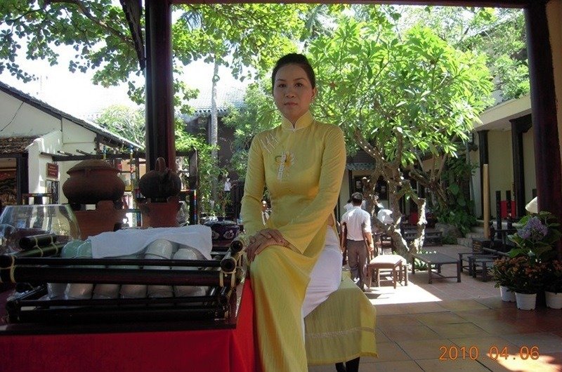 A Vietnamese woman in her yellow ao dai serving as a hostess in a club in Nha Trang